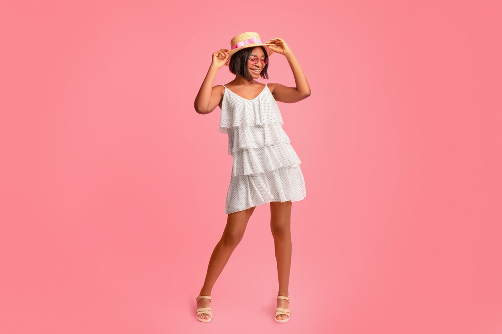 Positive black lady in fashionable summer clothes having fun, laughing and posing over pink background in studio, full length portrait. 