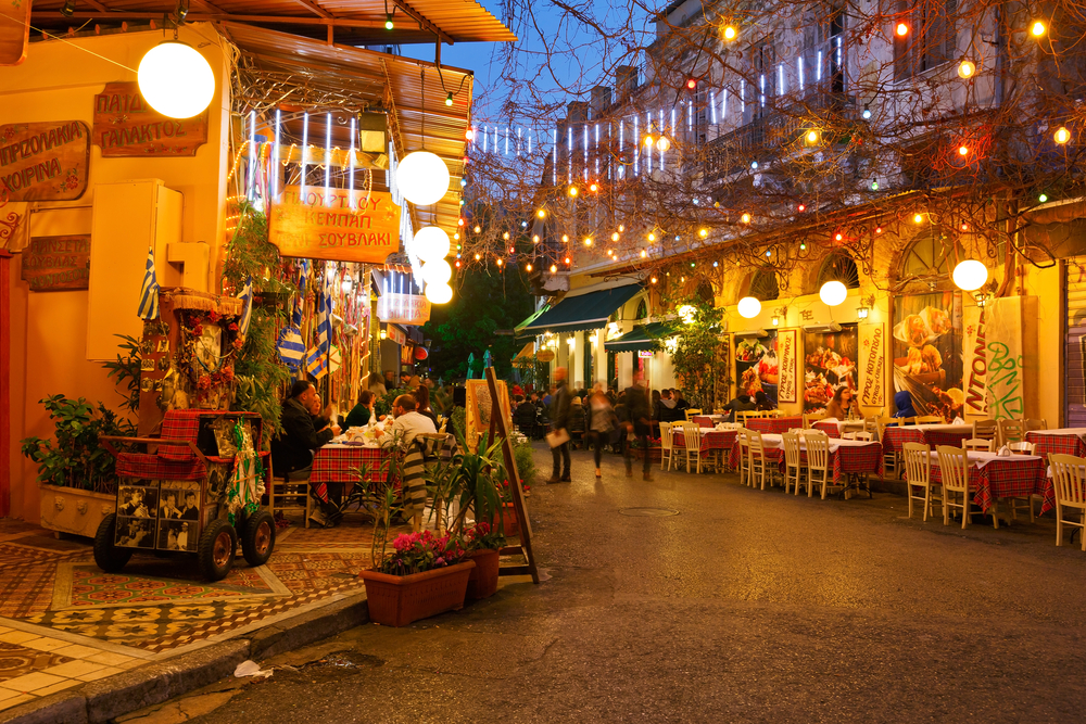 Restaurants and coffee shops illuminated with glowing lights at dusk.