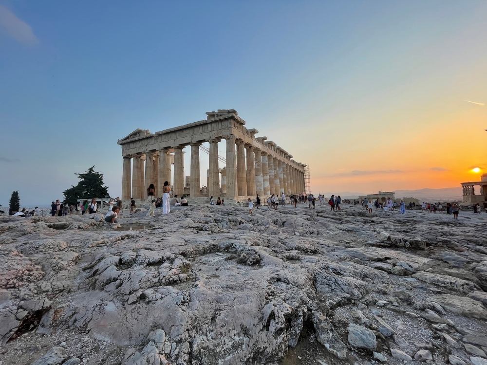 Parthenon Acropolis at sunset. There are people around the structure.