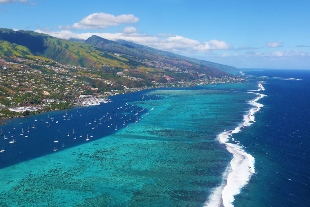 Aerial image of the ocean with boats and the mountains of Tahiti.