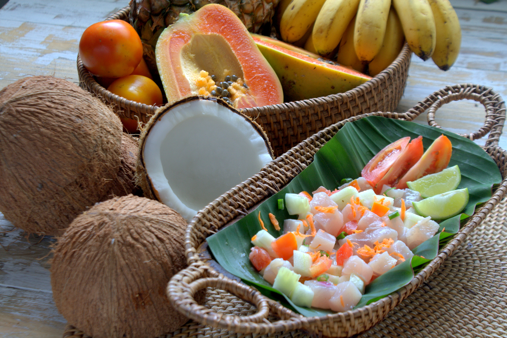A table set with a tuna salad and tropical fruit.