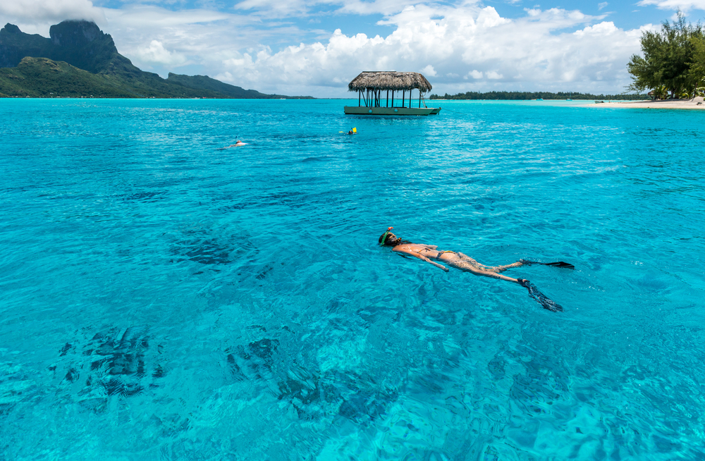 Photo of a woman swimming with snorkel gear in clear water when traveling to Bora Bora.