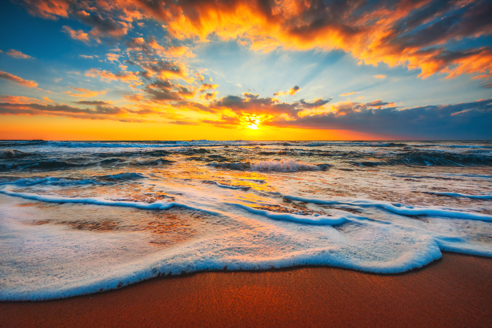 Close up image of the tide on a sandy beach at sunset.