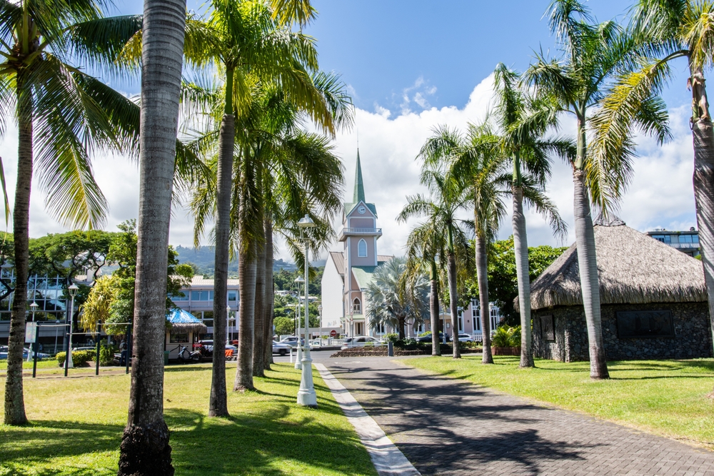 A street in Papeete, the capital of Tahiti, with palm trees and historic buildings.