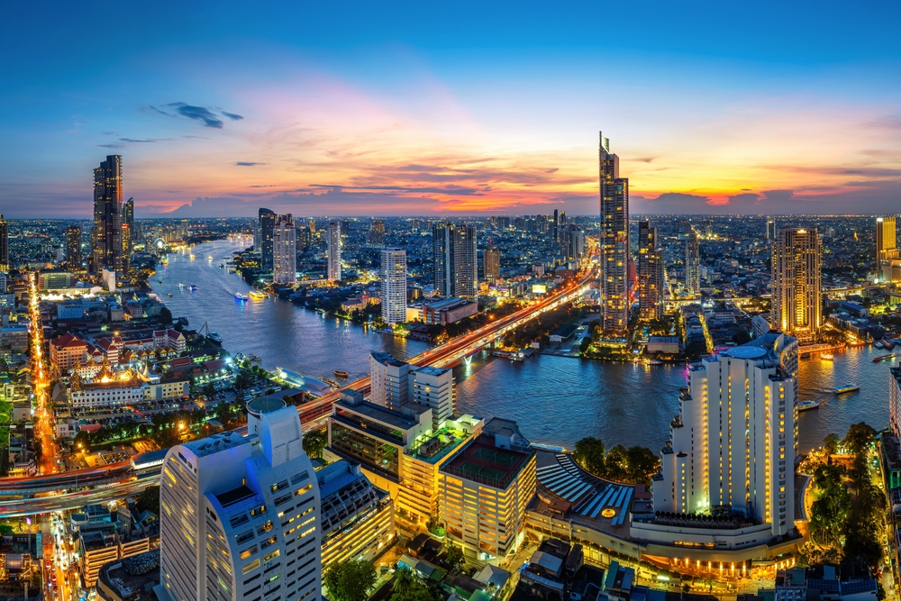 Aerial view of the city of Bangkok at sunset with the river winding through the skyscrapers.