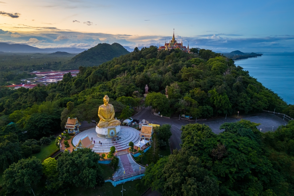Aerial view of sunset over Phra Mahathat Chedi Phakdee Prakat temple on Thong Chai Hill with rolling hills.