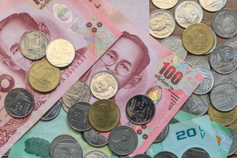 Assorted cash and coins of Thai Baht laid on a table.