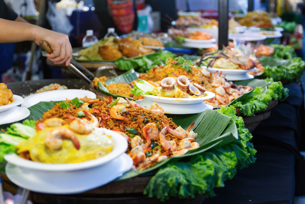 A street food market stall with many dishes laid out in Thailand.