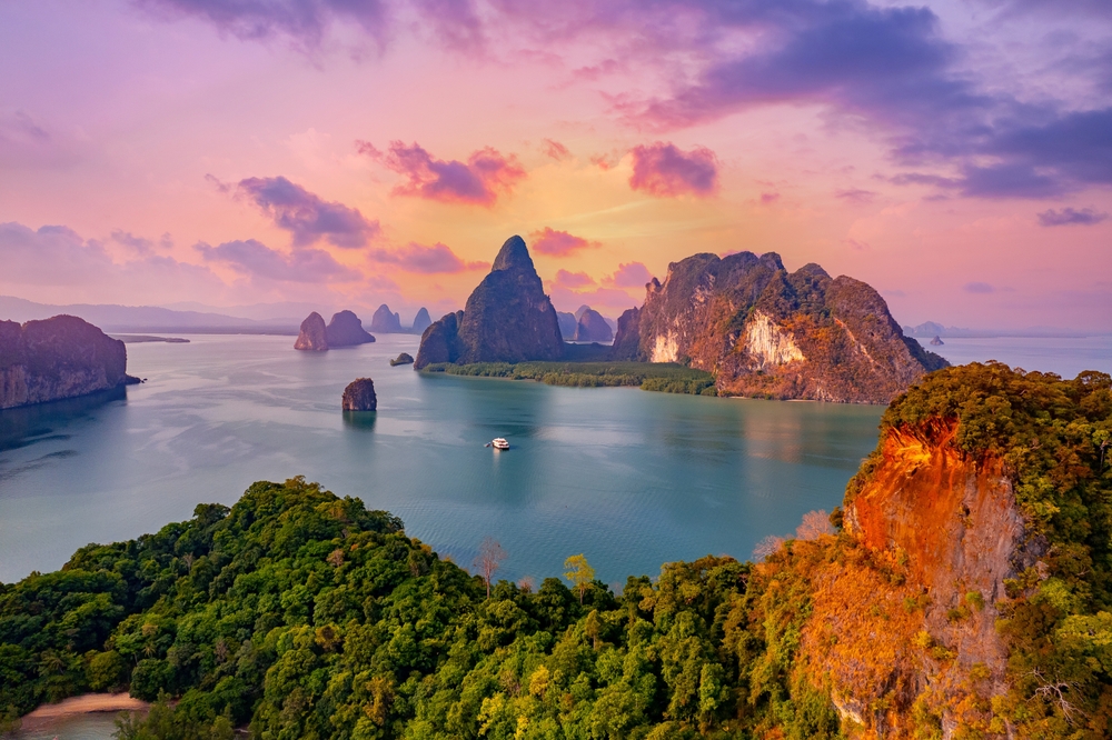Purple and pink sunset over Phang Nga bay with towering islands.