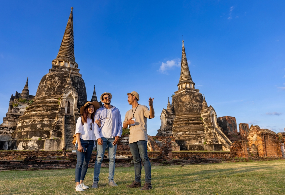 A couple listens to a tour guide talk at the historic temple of Ayutthaya.