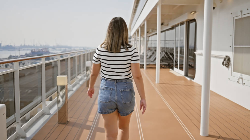 A,Rear,View,Of,A,Young,Adult,Woman,Walking,Alone A rear view of a young adult woman. wArticle is about Disney Cruise Outfits for Augustalking alone on a cruise ship deck with the ocean and sky in the background.