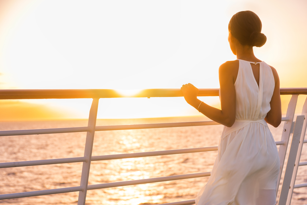 Cruise,Ship,Vacation,Woman,Enjoying,Sunset,On,Travel,At,Sea. Cruise ship vacation woman enjoying sunset on travel at sea. Elegant happy woman in white dress looking at ocean relaxing on luxury cruise liner boat.