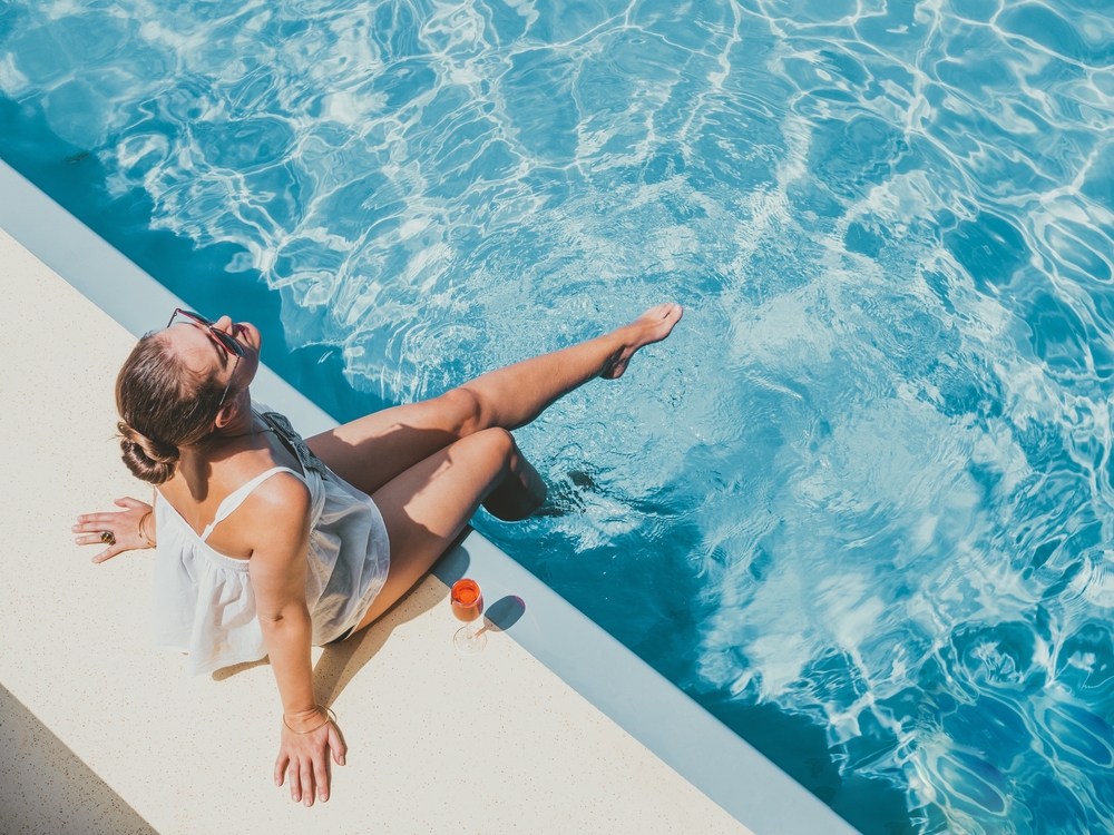 Fashionable,Woman,Sitting,By,The,Pool,On,The,Empty,Deck Fashionable woman sitting by the pool on the empty deck of a cruise liner. Article is about Disney Cruise Outfits for August