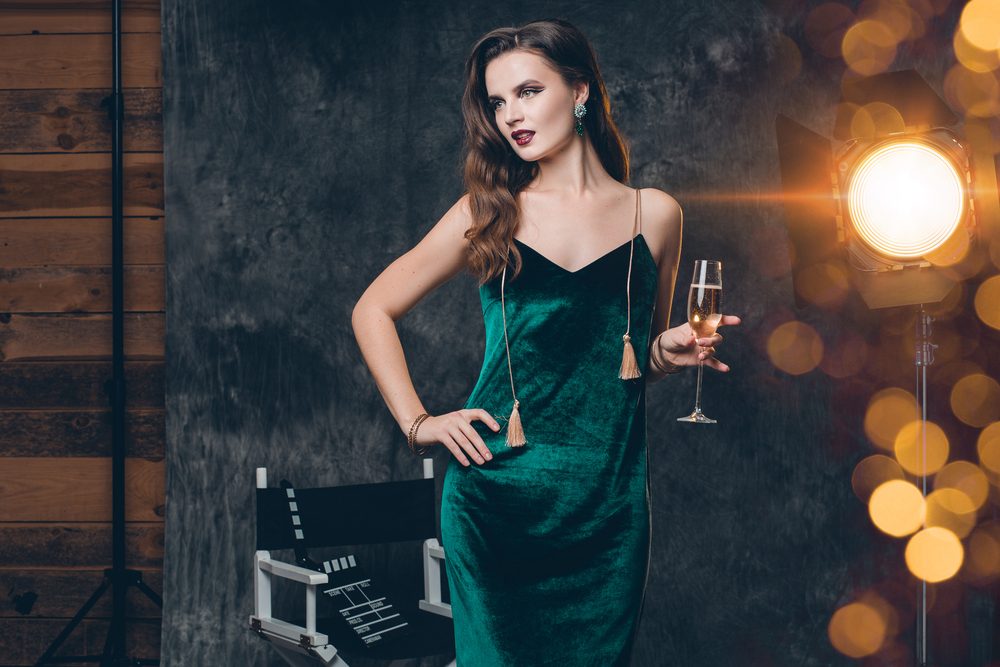 Young,Stylish,Sexy,Woman,On,Cinema,Backstage,,Celebrating,With,A Girl in green velet dress with champagne in her hand.