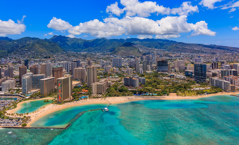 Aerial view of Waikiki Beach in Honolulu Hawaii from a helicopter showing the beach and hotels. The article is about Traveling to Hawaii.