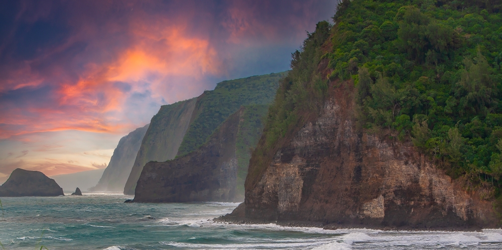 Sunset on the North Shore Big Island of Hawaii. The headlands fall almost vertically into the ocean near the Pololu Valley. The article is about Traveling to Hawaii.