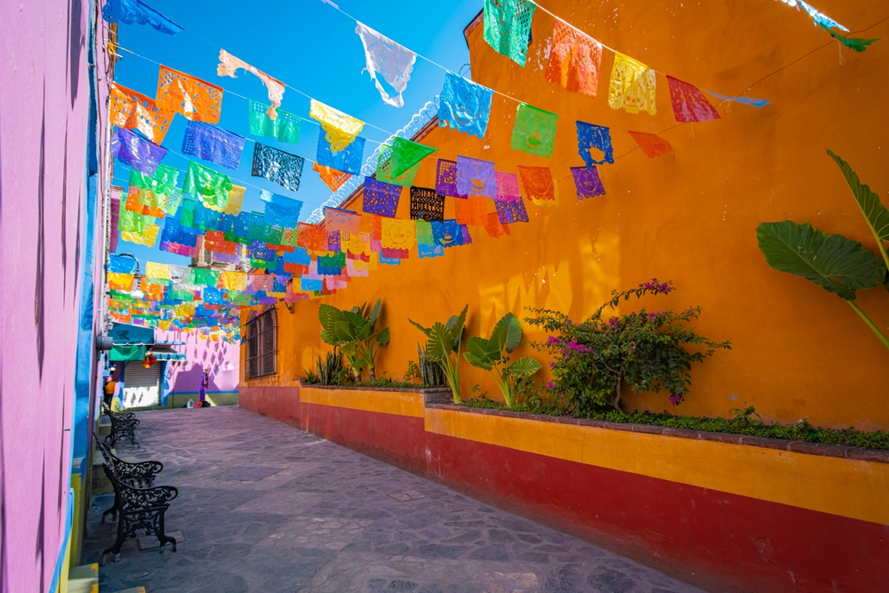 Panoramic view of a picturesque street in the town of Zimapán decorated with colorful pennants on a sunny day. This article is about traveling to Mexico.
