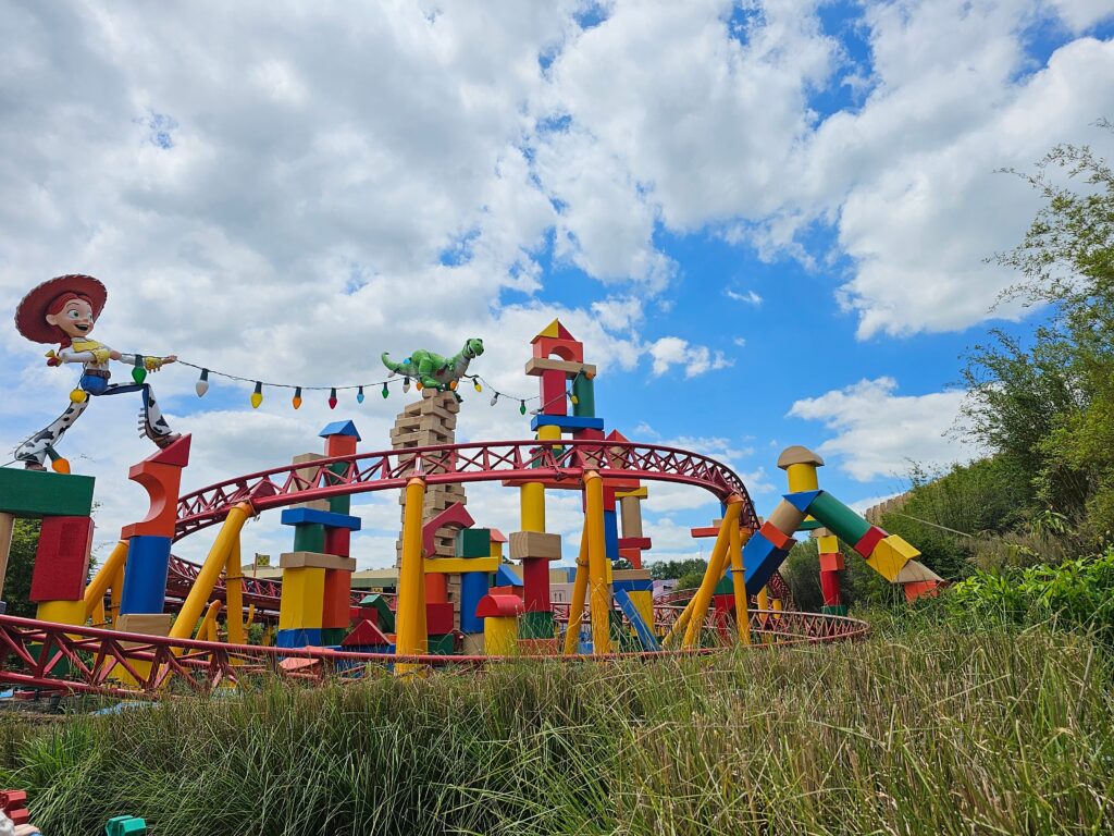 Brightly-colored roller coaster with large character figure laughing.