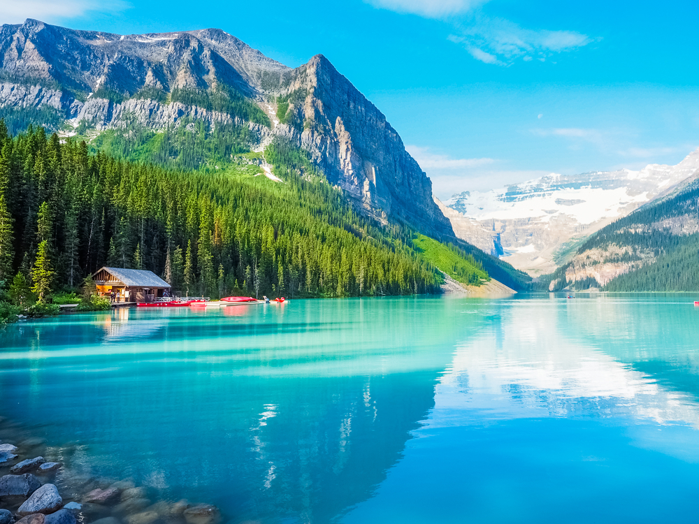 clear blue lake with a small hut and trees and mountains surrounding it things to do in banff