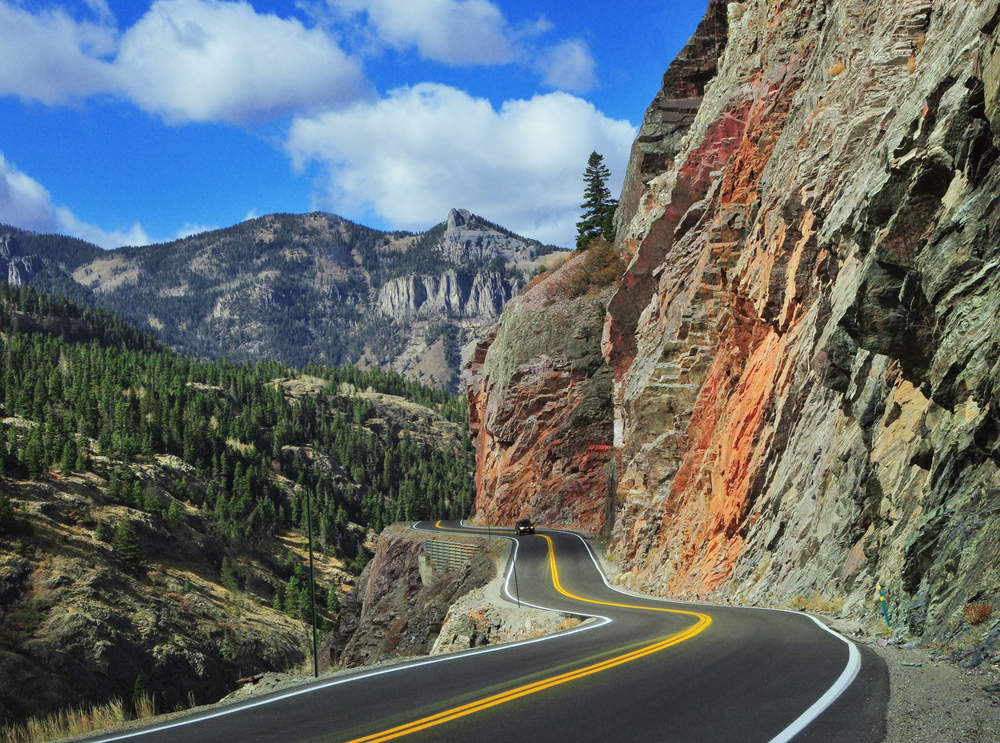 Car driving on mountain road. There is a large drop off one side.  
