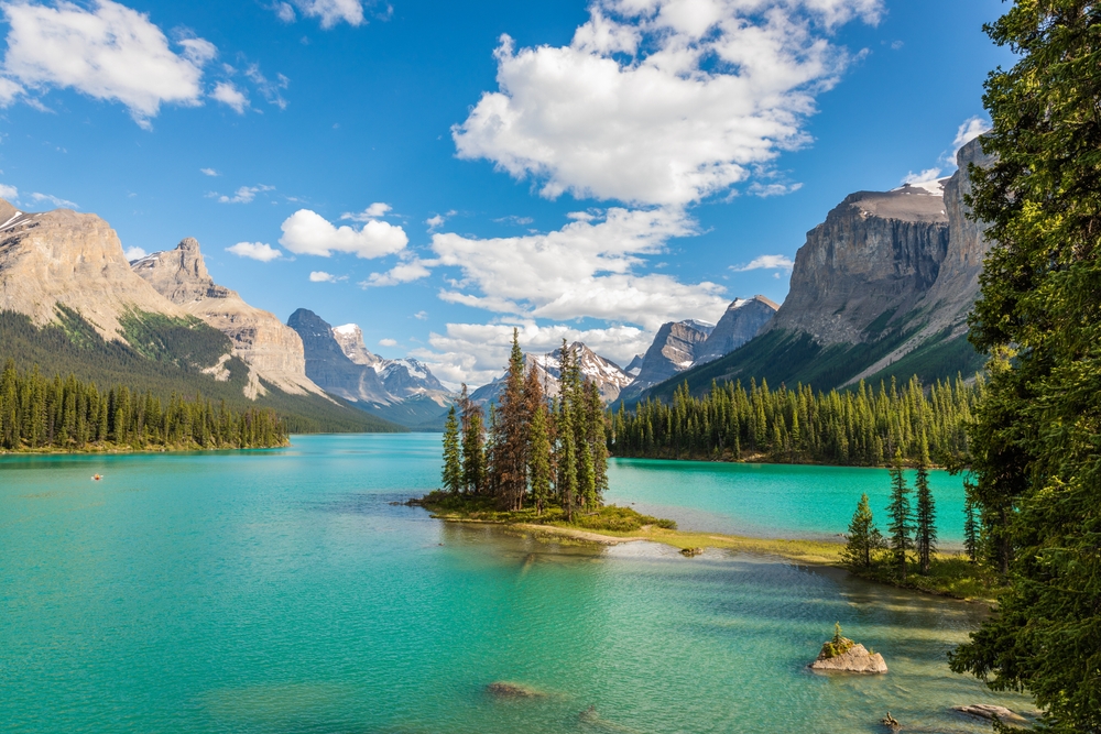 lake with a small island surrounded by mountains and forests