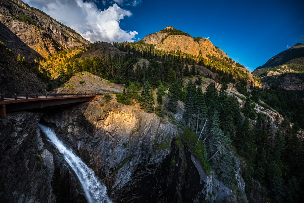 Bear Creek Falls bridge at Million Dollar Highway with Mt Abram Colorado. The article is about things to do in Colorado. 