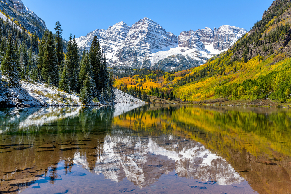 Maroon Bells and Maroon Lake - A wide-angle autumn midday view of snow coated Maroon Bells reflecting in crystal clear Maroon Lake, Aspen, Colorado, USA. 