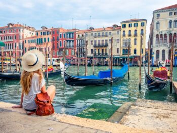 girl sitting on a harbour enjoying the city views and boat view traveling to italy