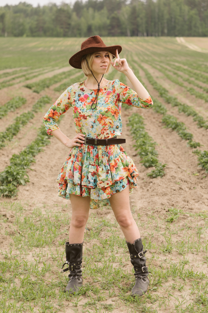 Cowboy girl in the field wearing a dress and boots.  article is about Austin outfits 