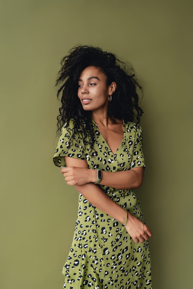 woman posing in stylish green leopard printed dress isolated on green studio background.