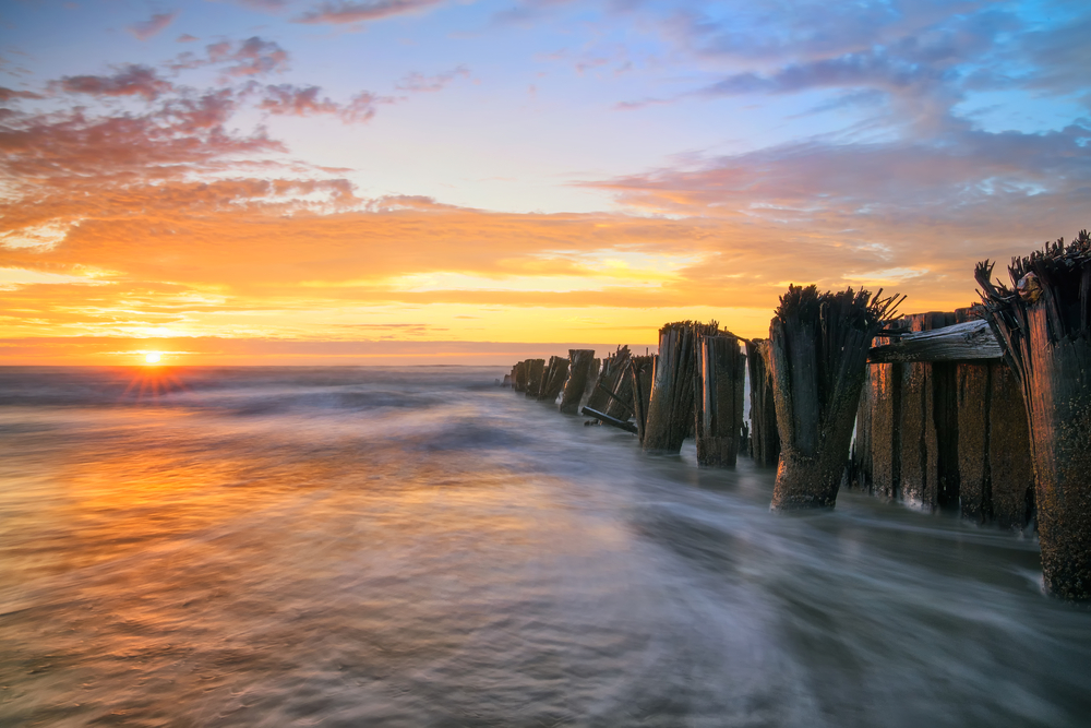 Folly Beach Sunrise Landscape Scene with Wood Jetty. The article is a Charleston Travel Guide.