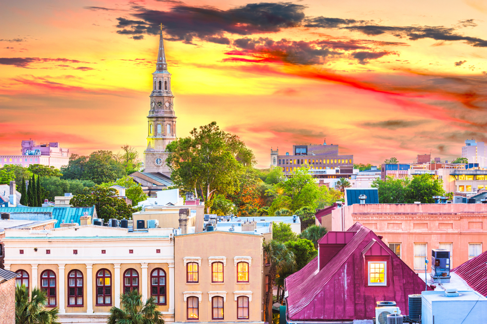 Charleston, South Carolina, USA town skyline at dusk.. You are see a church tower and buildings. The article is a Charleston Travel Guide