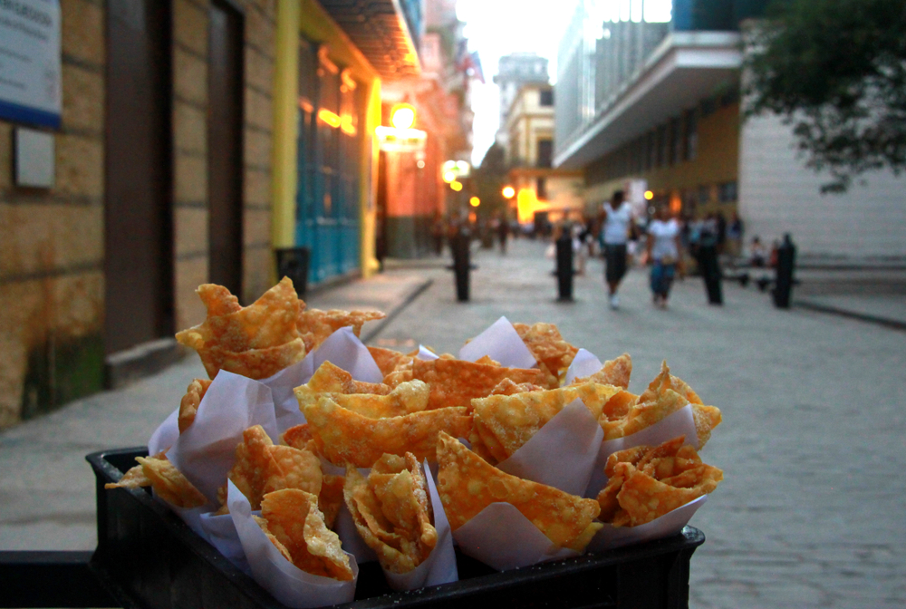 Street food held on a basket. The street and people are behind.