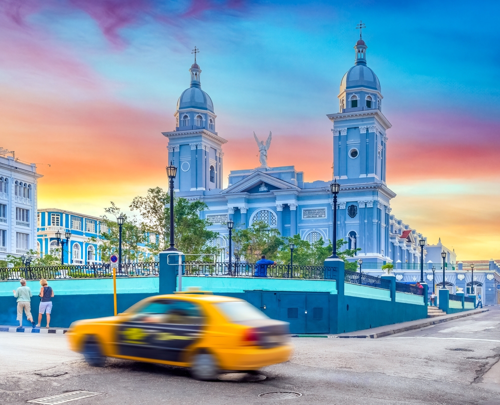 Blue ornate in background with blurred yellow taxi in foreground.