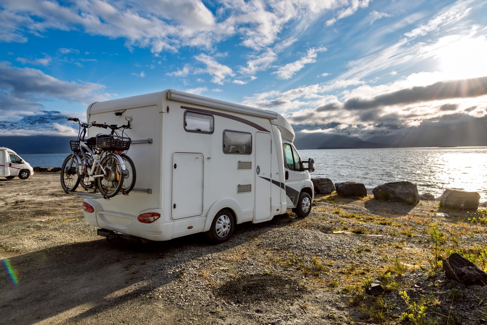 campervan parked beside a lake with cycle behind traveling to norway