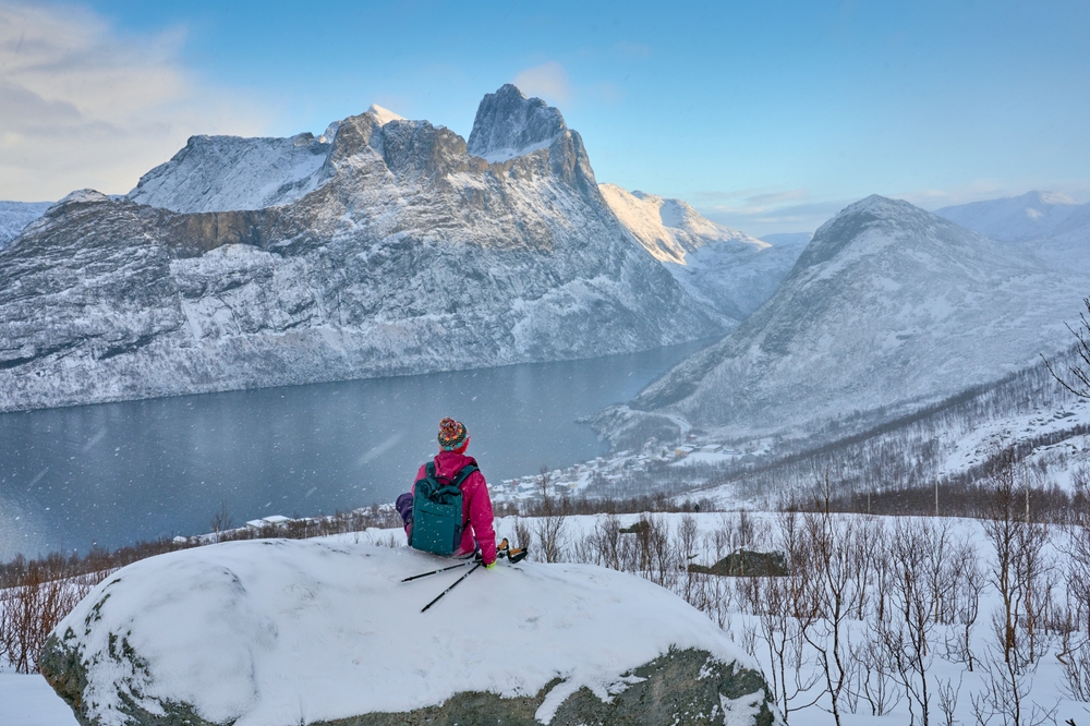 woman wearing winter gear and hiking through snowy mountains traveling to norway