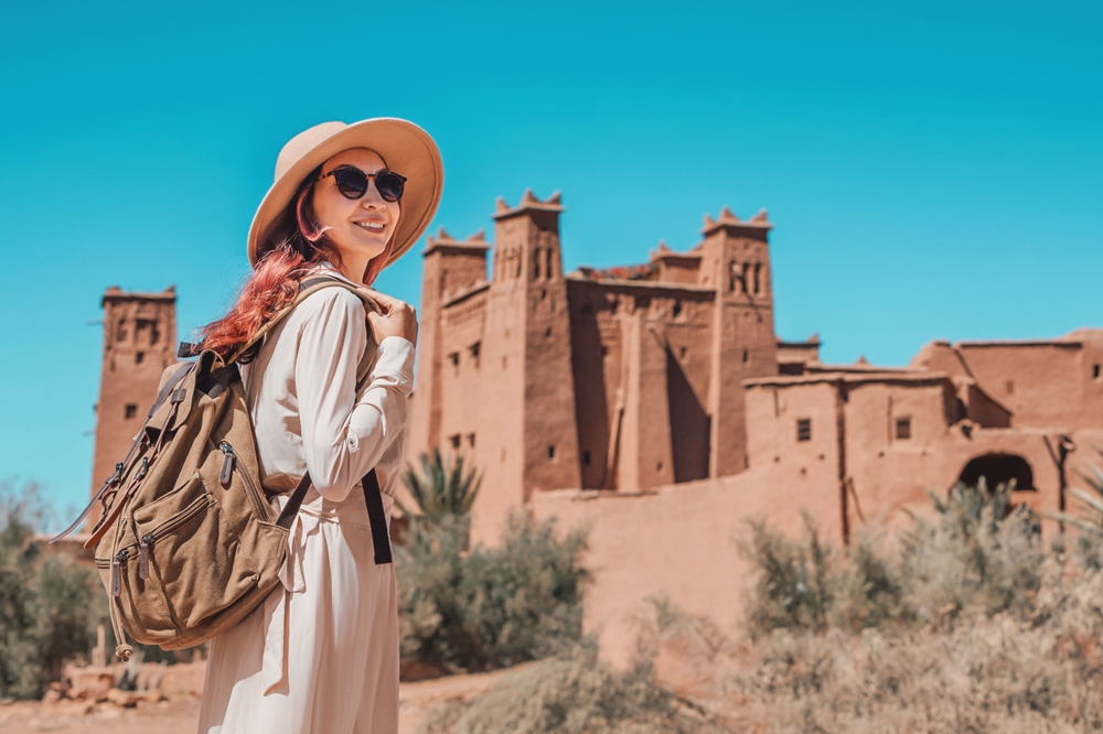 girl with a backpack and hat exploring old fortress traveling to morocco