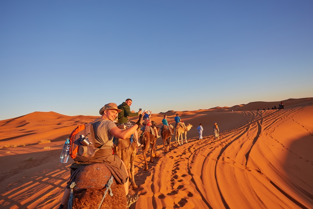 group of people going on a camel ride through the desert traveling to morocco