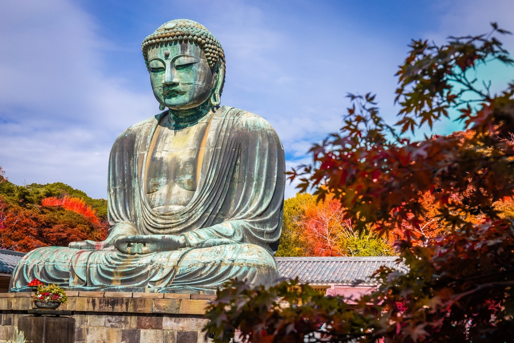 Daibutsu or Great Buddha of Kamakura in Kotokuin Temple at Kanagawa with autumn leaves around it. The article is about a Day Trip to Kamakura