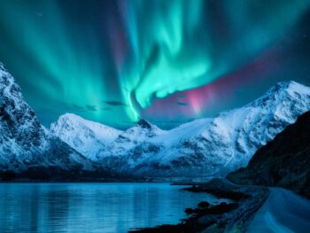 northern lights over snowy mountains traveling to norway