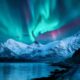 northern lights over snowy mountains traveling to norway