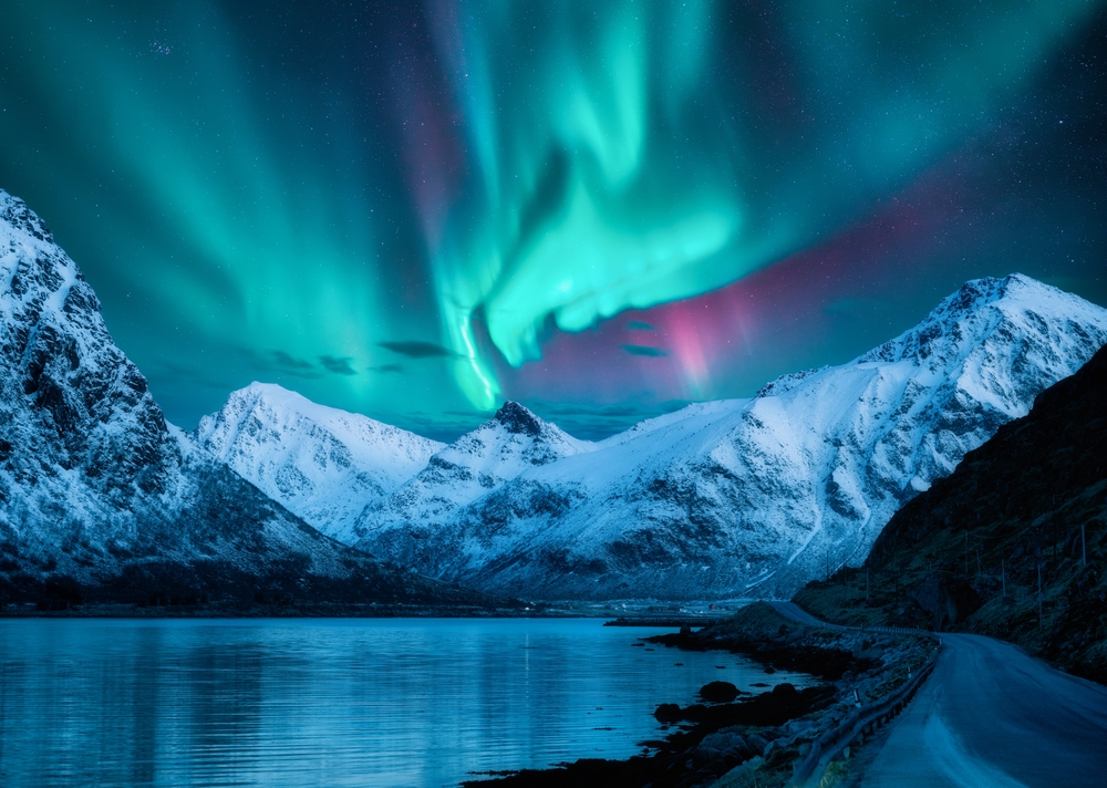 northern lights over snowy mountains traveling to norway