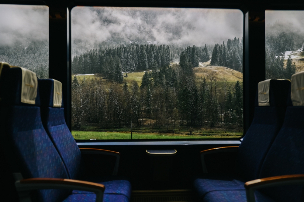 inside a train with large windows and mountain views european train trips