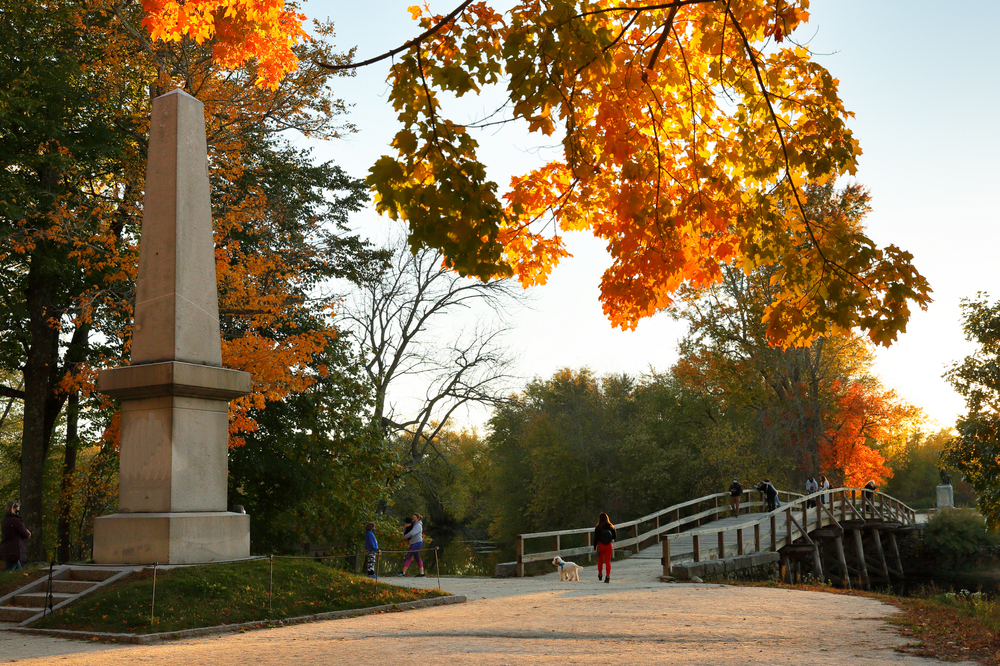The Memorial Obelisk of North Bridge, often colloquially called the Old North Bridge in Concord. you can see people walking on the bridge. 