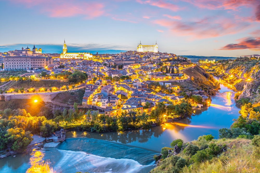 view of a town surrounded by river lit up during sunset things to do in madrid