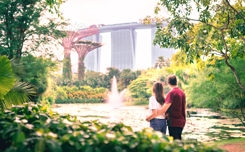 Couple looking at the city of Singapore with Marina Bay Sands hotel and Gardens by the Bay nature park.