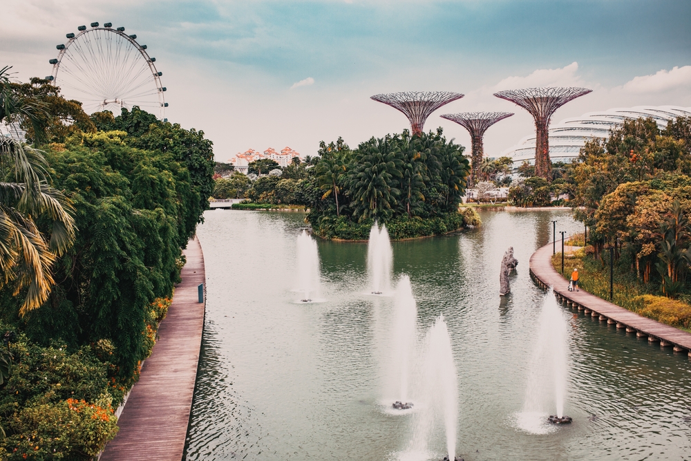 Amusement park in background and ornamental structures with water and fountains in foreground.