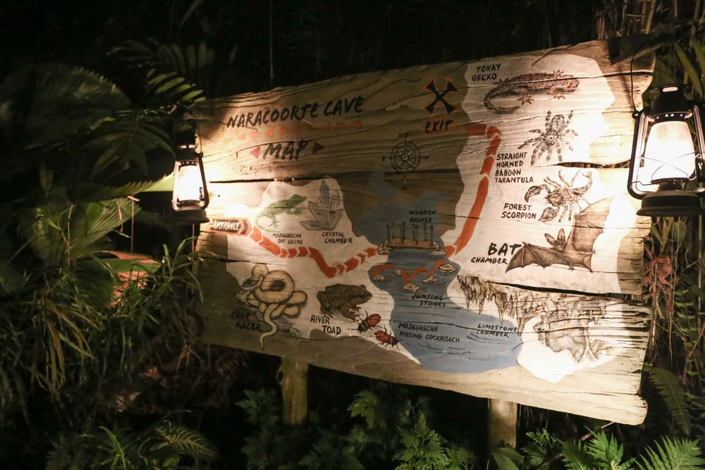Illuminated wooden sign surrounded by greenery