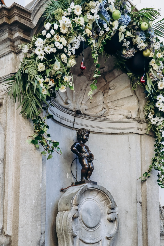 Manneken Pis (Dutch for 'Little Pissing Man'), a landmark 55.5 cm bronze fountain sculpture in central Brussels surrounded by flowers 