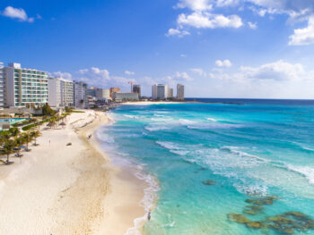 beach with buildings and clear blue water cancun travel tips